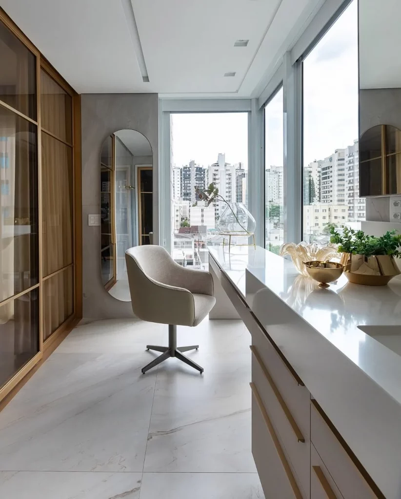 Penteadeira e pia linear perto de janelas e com closet no fundo.