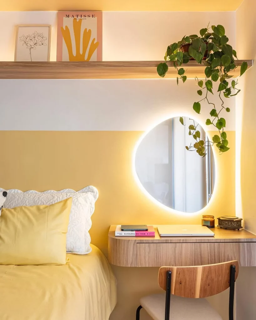 Penteadeira no quarto com parede amarela e iluminação.