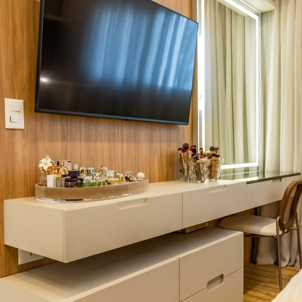 Penteadeira na sala de tv com espelho grande no painel com luz de LED embutida.