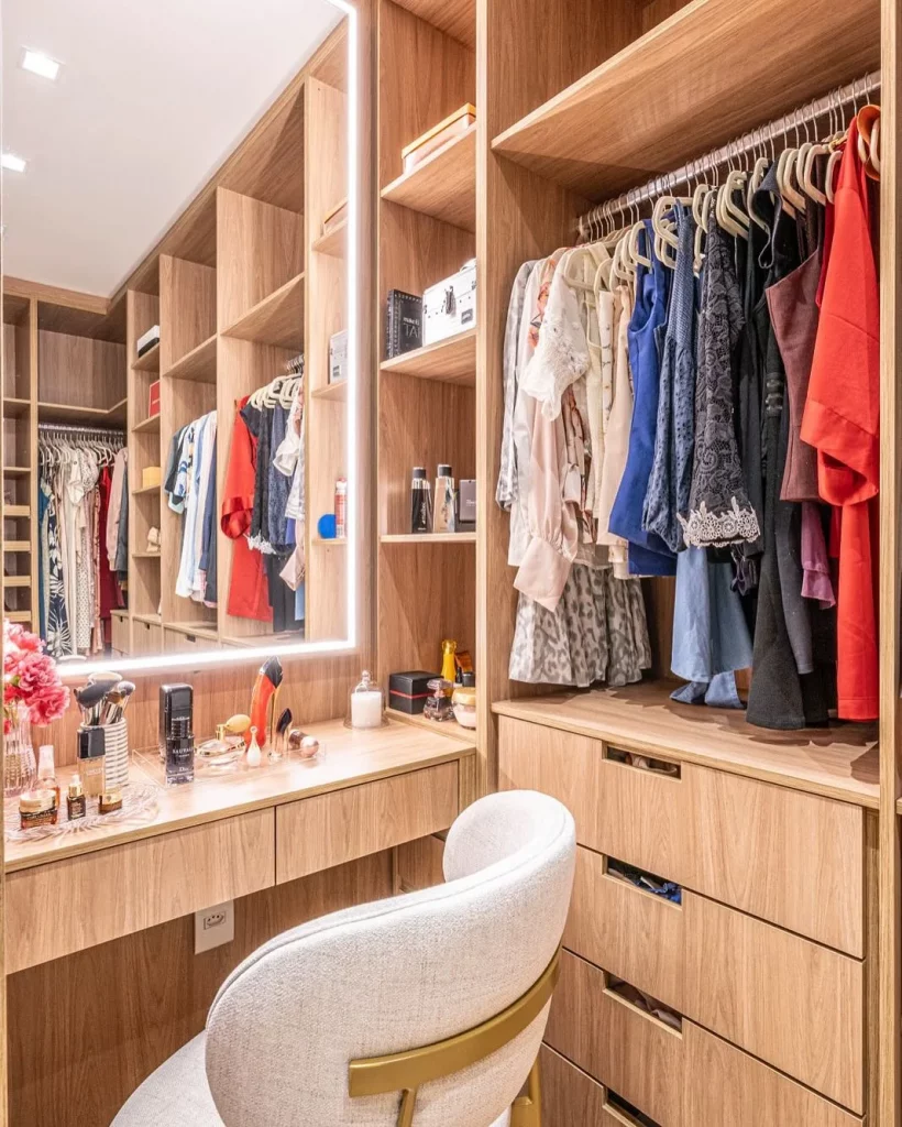 Closet de madeira clara com luz embutida no espelho da penteadeira.