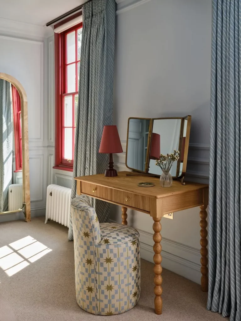 Penteadeira com pés de bolinhas e abajur em cima da madeira.