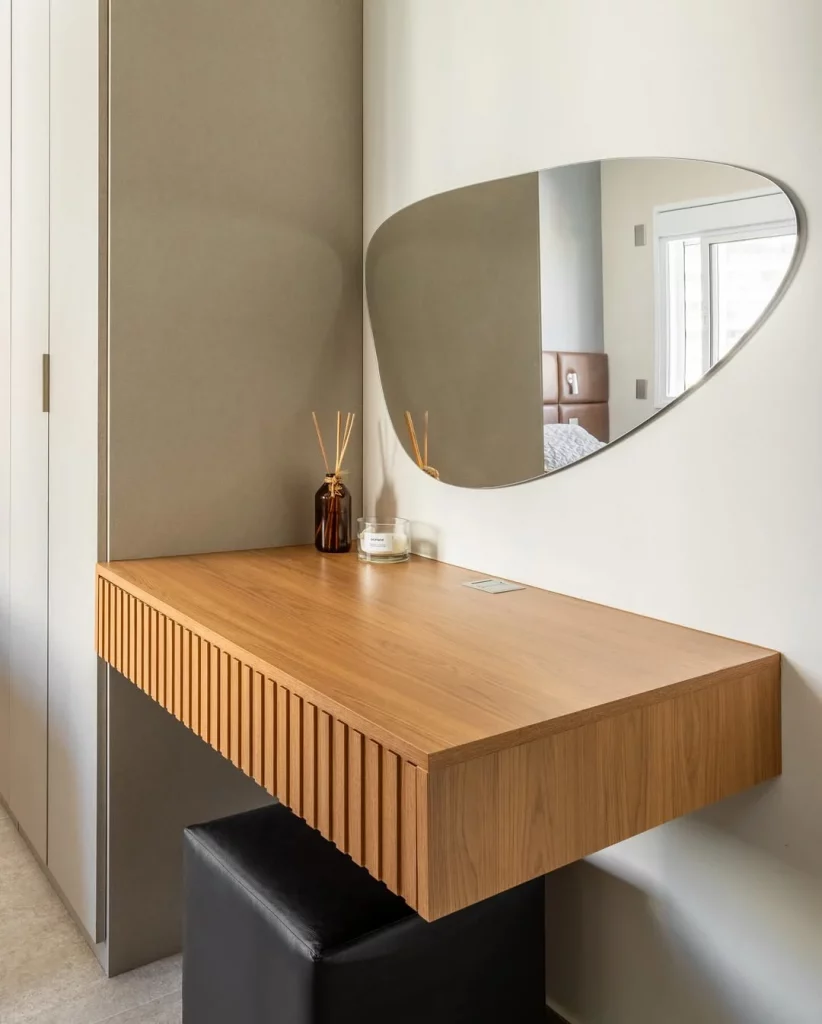 Penteadeira suspensa com espelho orgânico e efeito ripado.