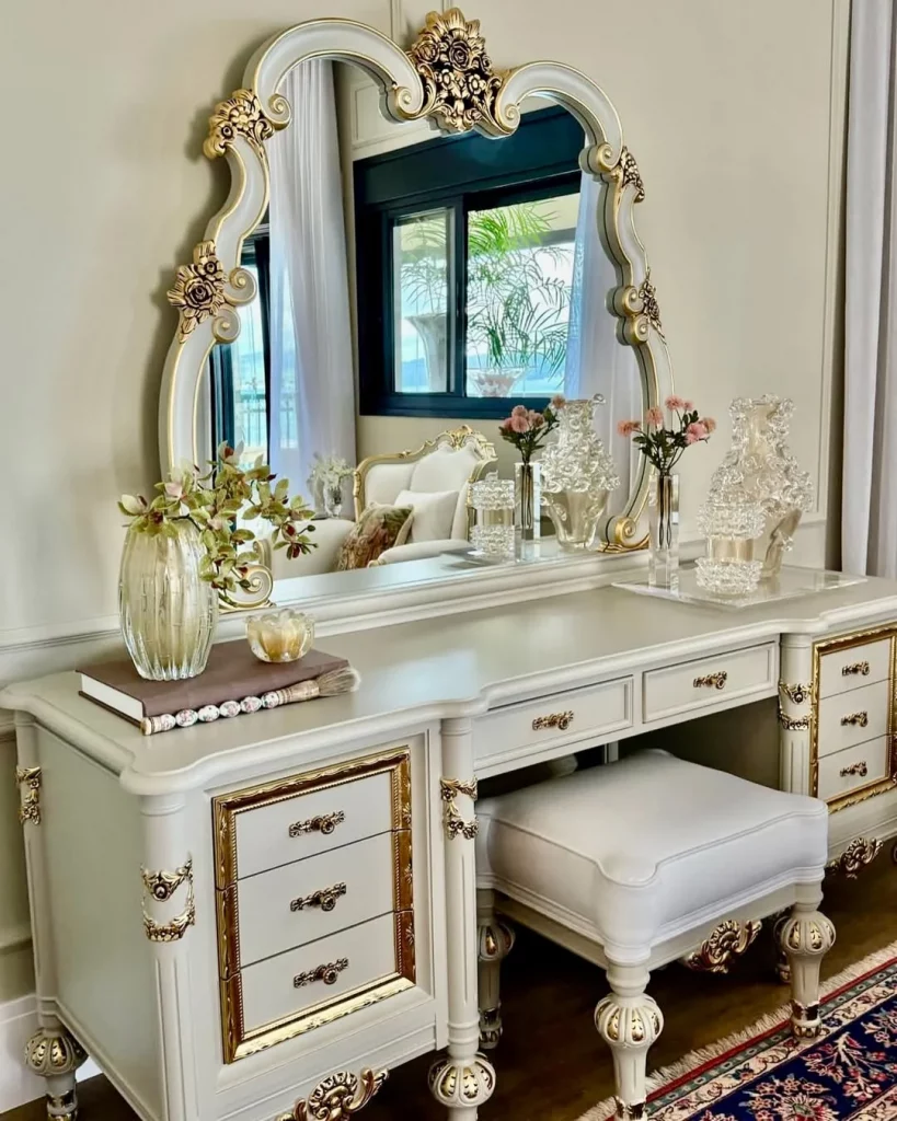 Penteadeira com muitos detalhes no espelho e puxadores, nas cores dourado e branco, com banco.