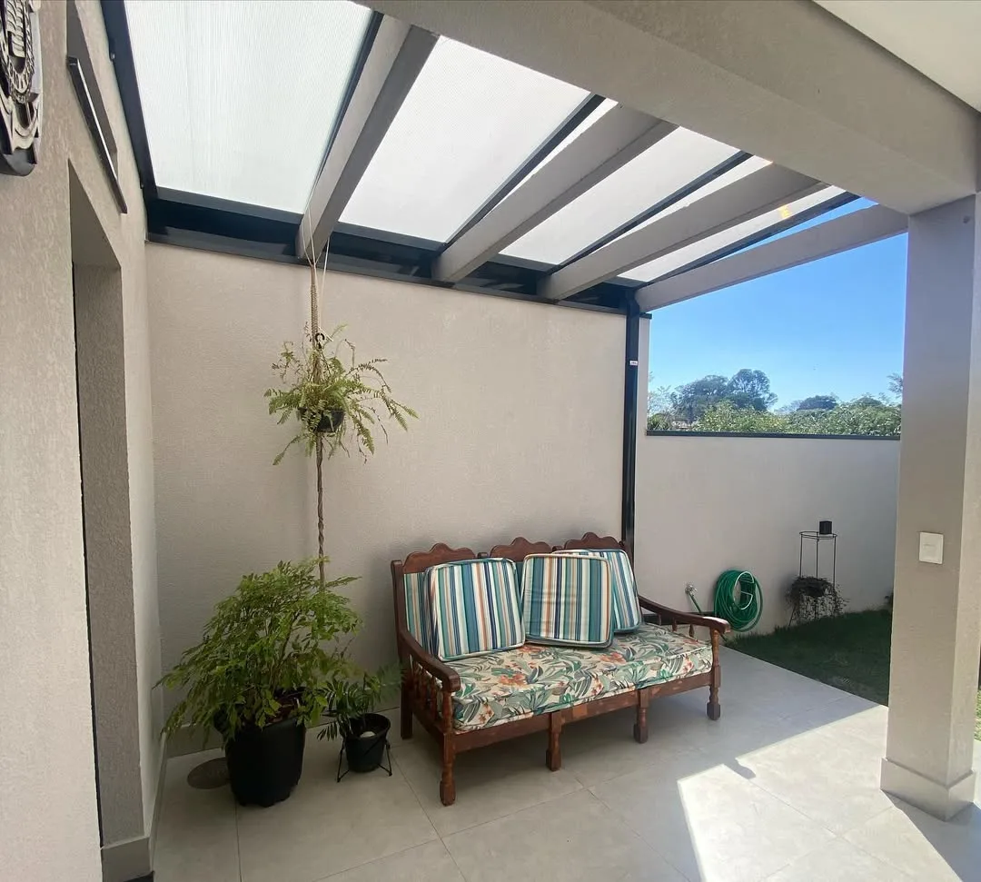 Pergolado de concreto forrado, plantas na parede e sofá.