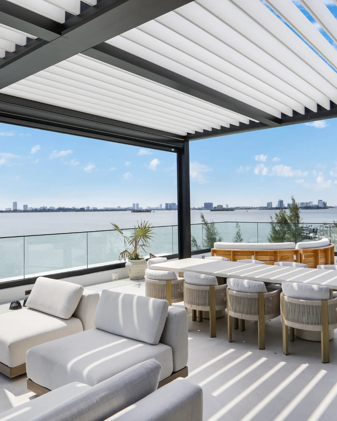Pergolado preto no rooftop com forro, cadeiras e mesa branca.