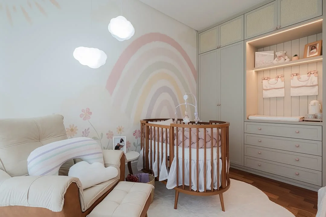 Quarto de bebê com pintura de arco-íris e berço de madeira.