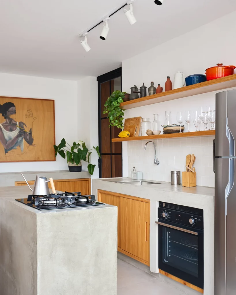 Prateleira de madeira com utensílios domésticos nela, eletrodomésticos e balcão cinza.