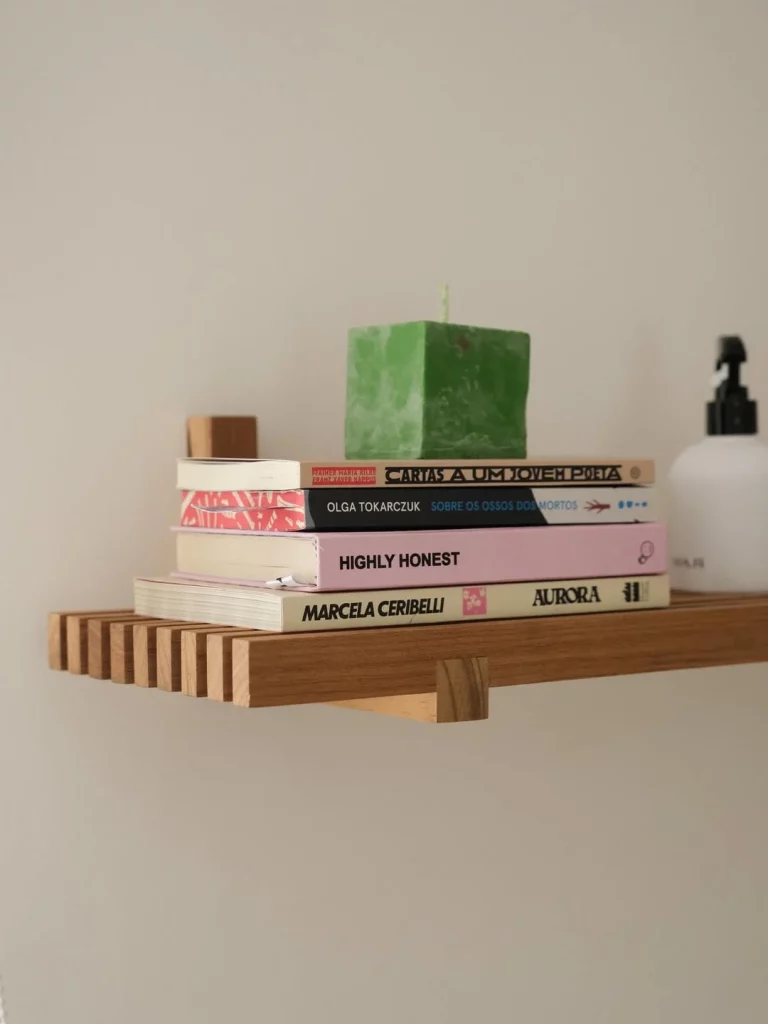 Prateleira de madeira ripada com livros.