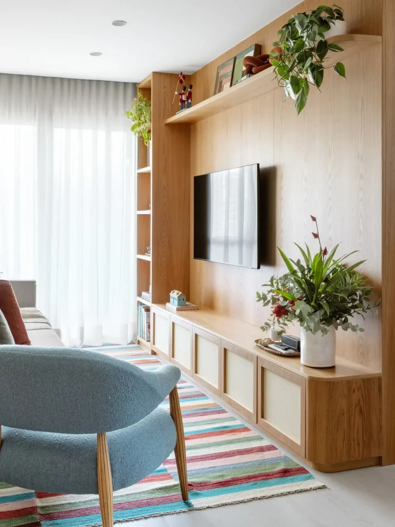 Prateleira de madeira com televisão e poltrona azul.