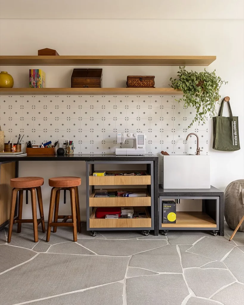 Prateleira de madeira clara com ferramentas, sacola pendurada na parede e duas banquetas.