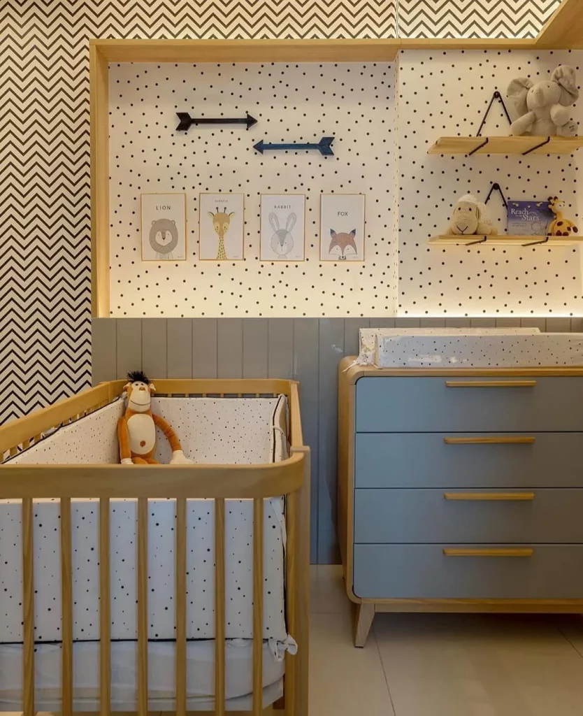 Prateleiras de madeira no quarto de bebê com papel de parede e cômoda azul.
