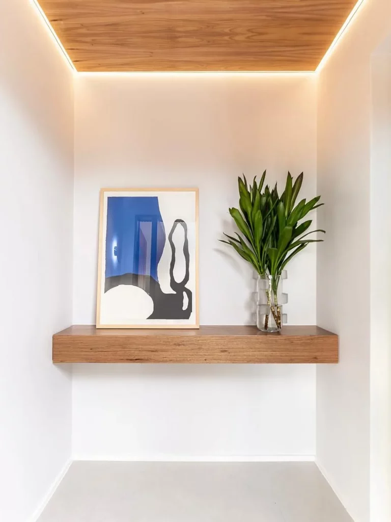 Prateleira suspensa no hall de entrada com iluminação no teto.