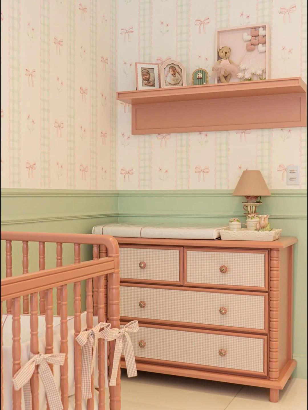 Quarto de bebê com boiserie verde, móveis rosa.