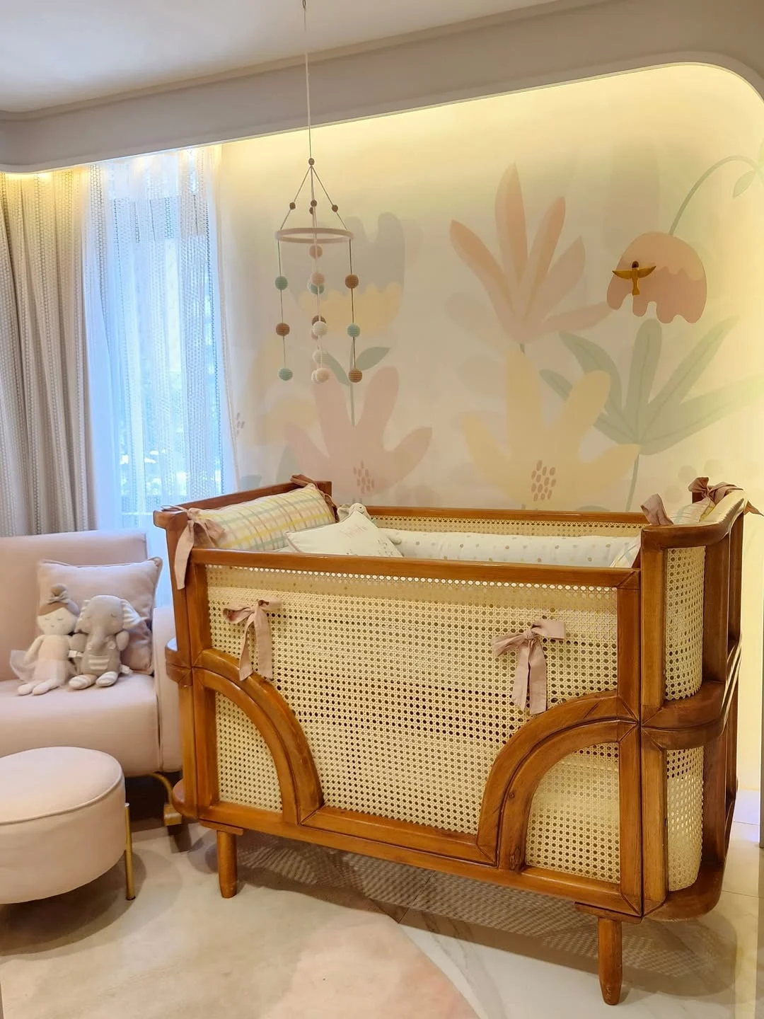 Quarto de bebê com desenhos na parede de flores, berço bonito de madeira e palha.