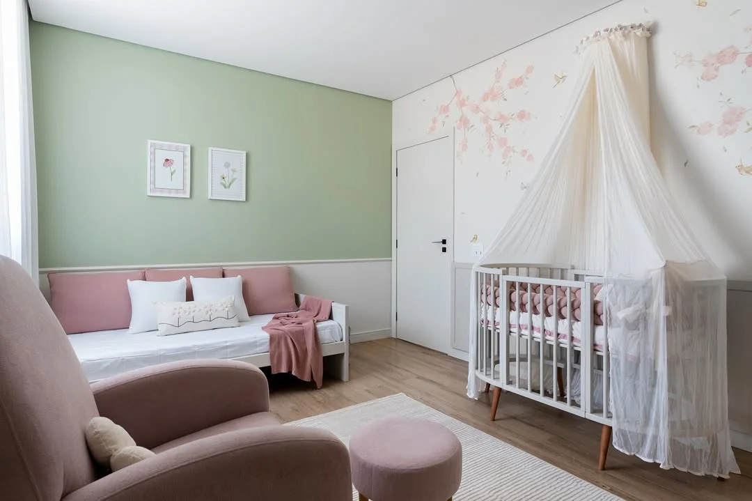Quarto de bebê com parede verde e pintura, poltrona rosé.