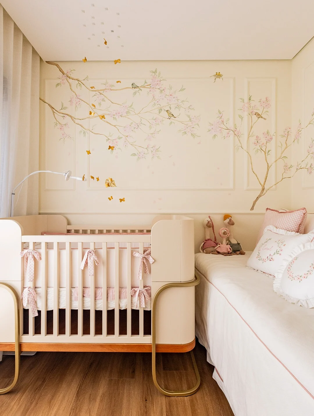 Quarto de bebê pequeno com pintura na parede, berço e sofá.