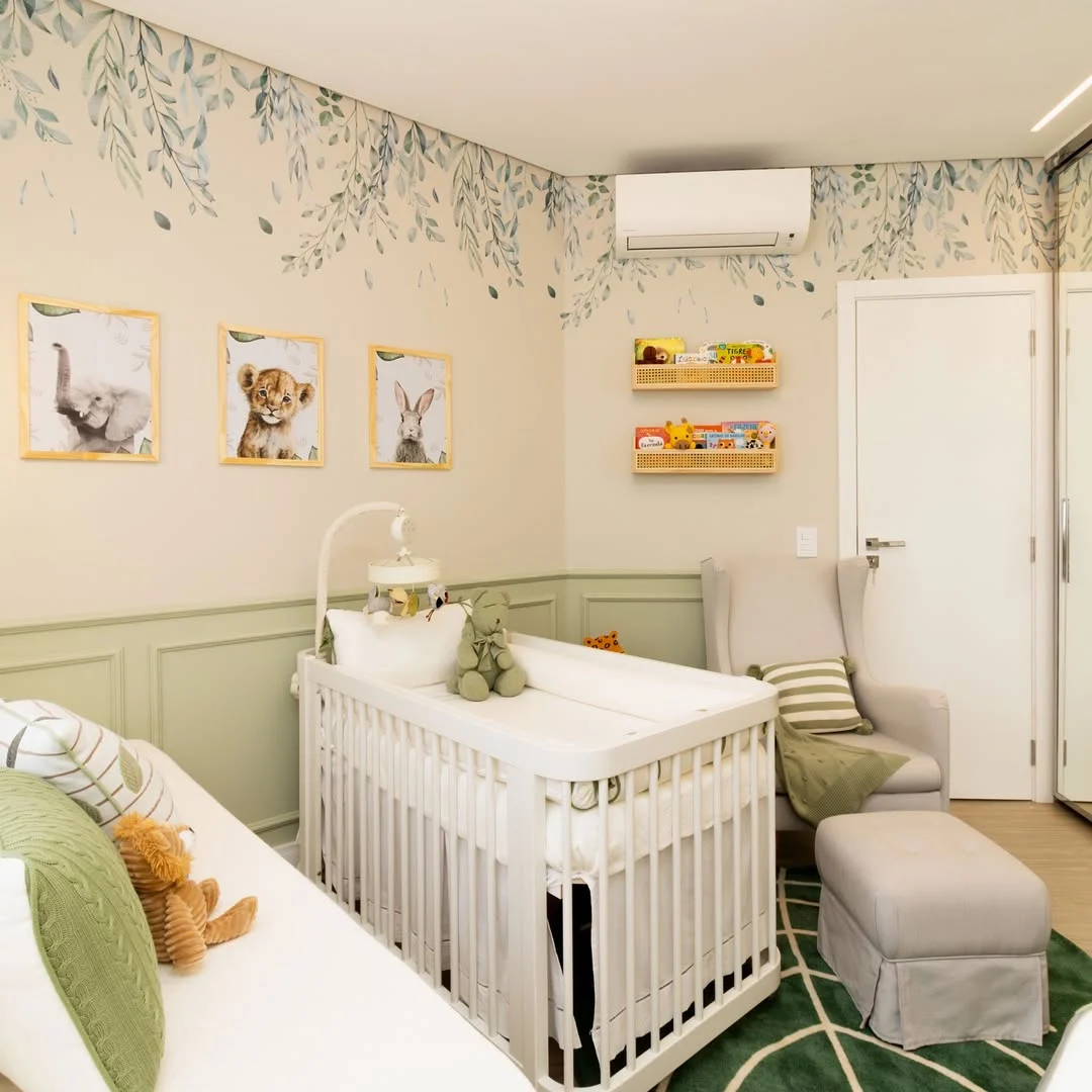 Quarto de bebê com boiserie verde, pintura saindo do teto e berço branco.