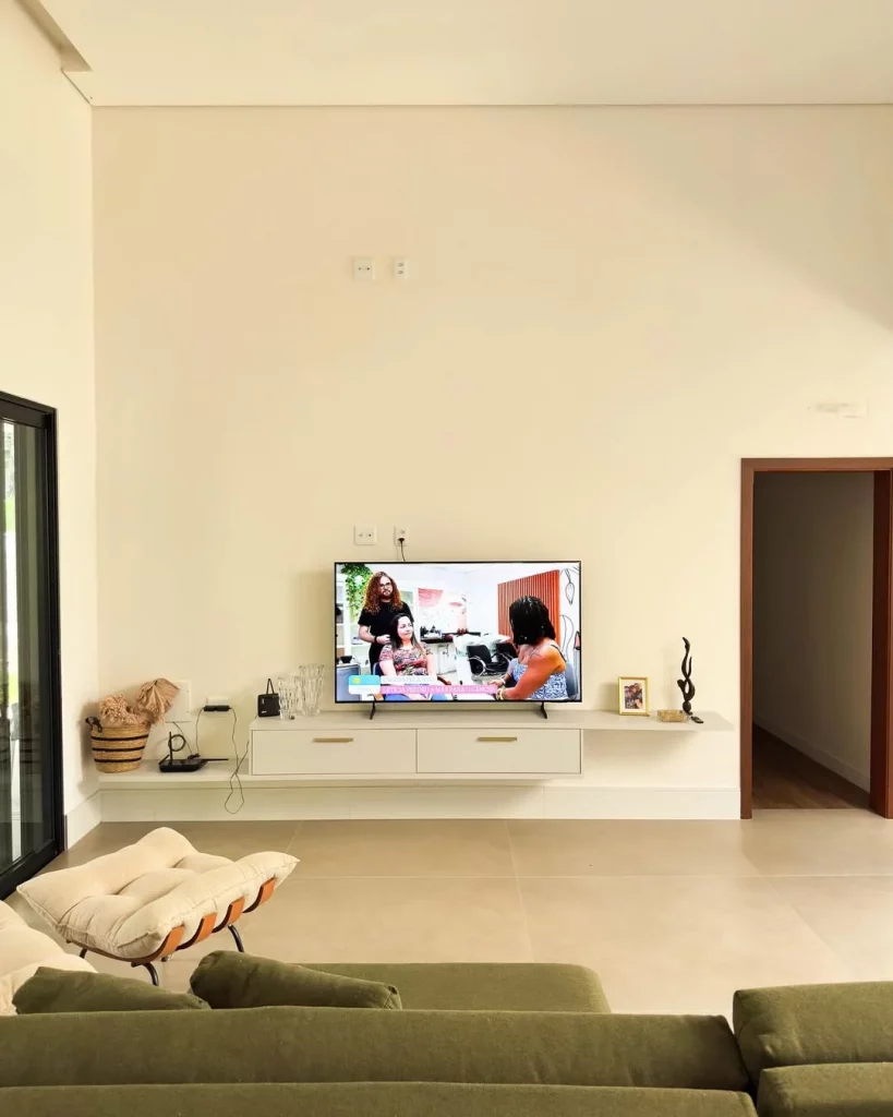 Rack suspenso branco com televisão apoiada em cima dele.