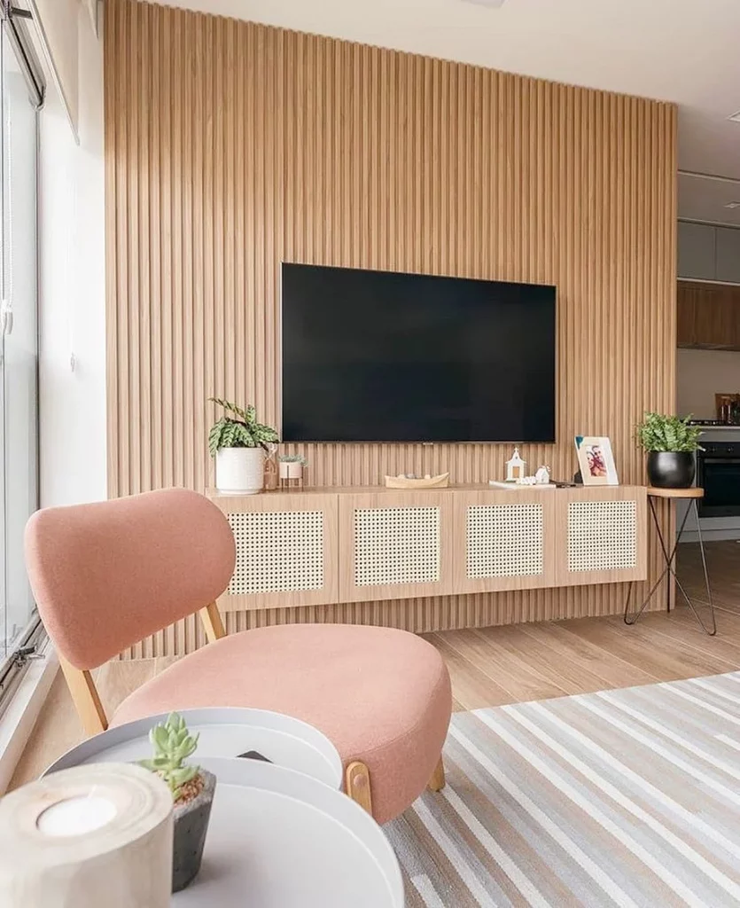 Rack suspenso com televisão, cadeira rosa e madeira clara.