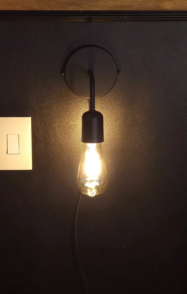 Iluminação com arandela preta e luz amarelada.