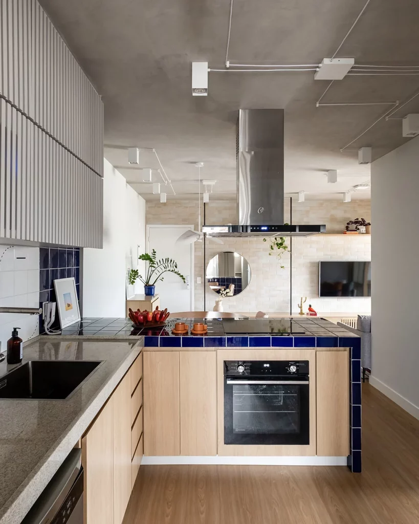 Cozinha planejada com armário de madeira clara e bancada cinza com azulejo.