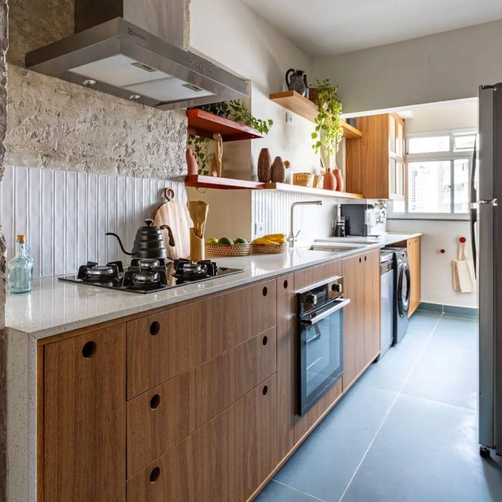 Cozinha com bancada branca e armário de madeira, utensílios em cima.