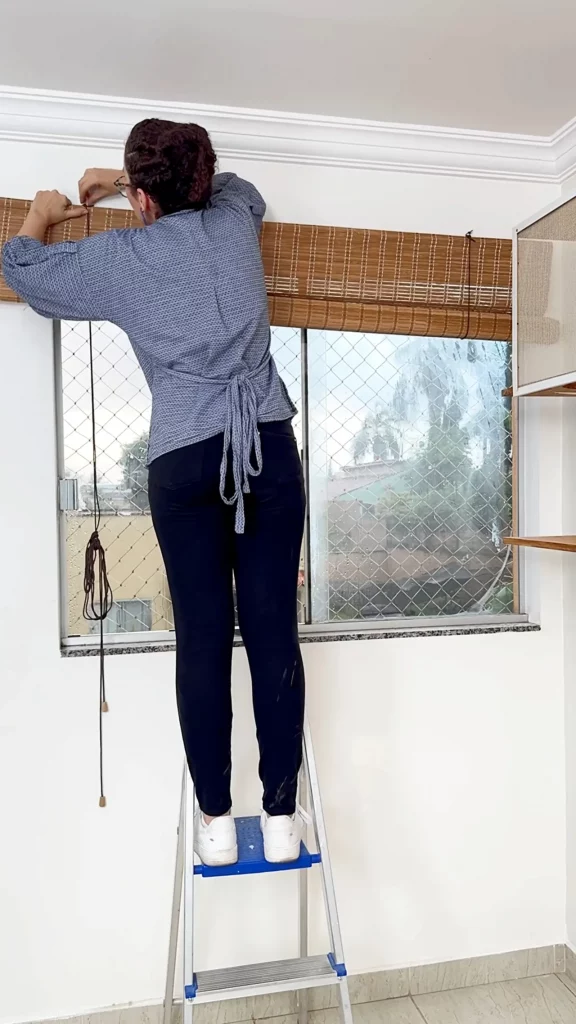 Instalação de cortina de bambu marrom na janela de vidro.