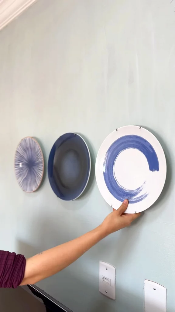 Colocando pratos decorativos na parede azul.