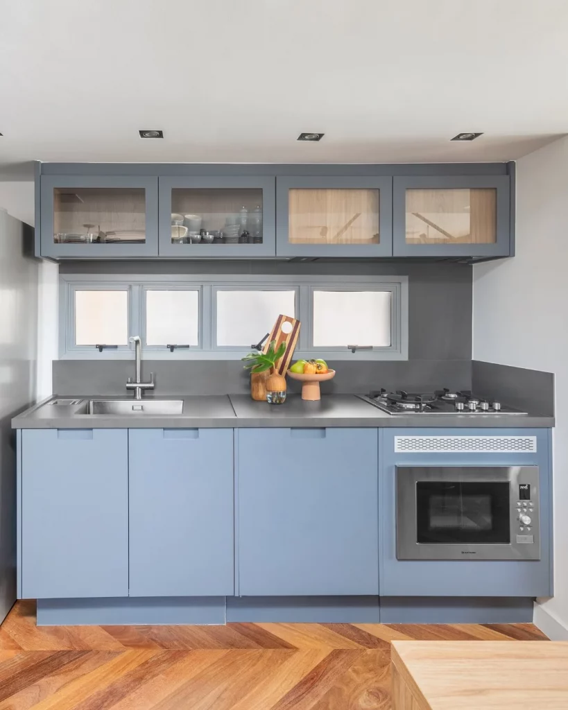 Cozinha com armário azul e bancada cinza.