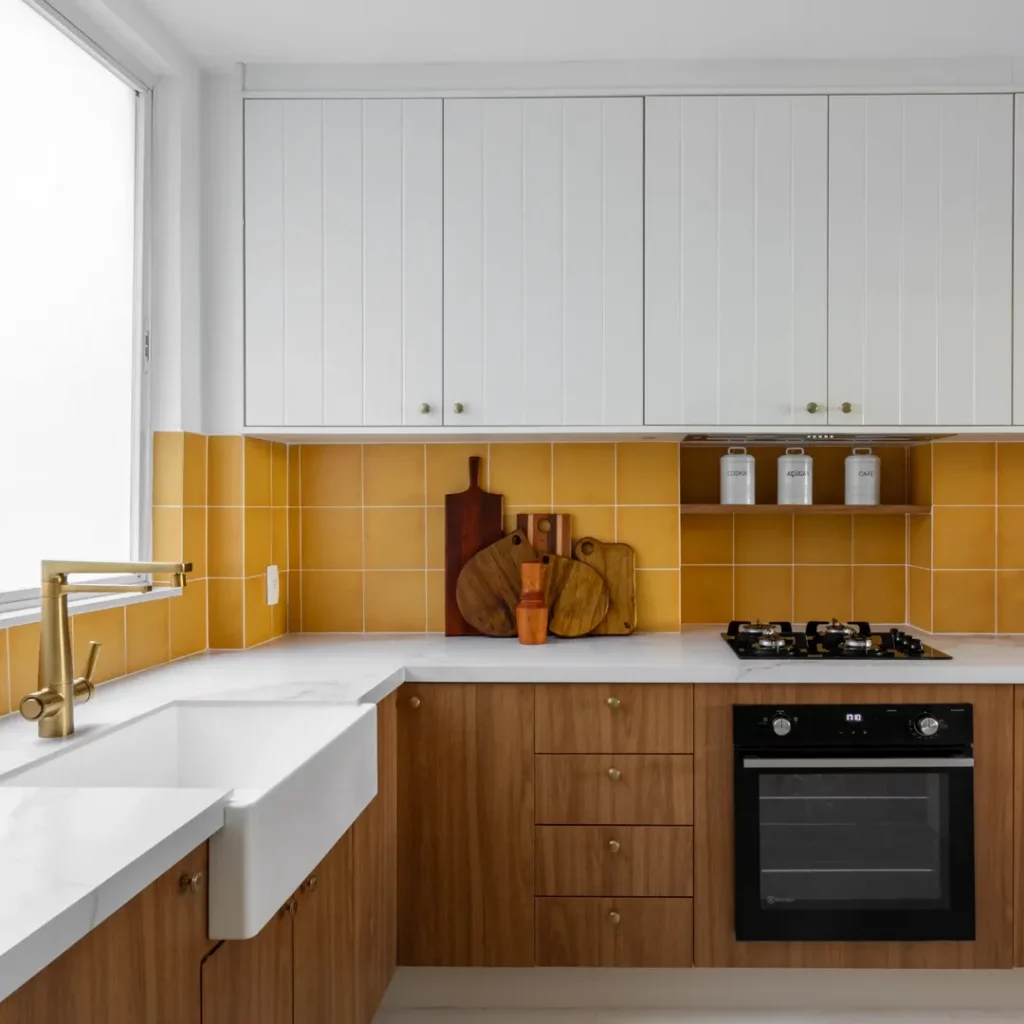 Bancada de cozinha branca com azulejo amarelo mostarda e armário de madeira.