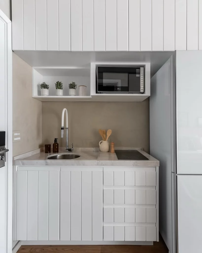 Cozinha com bancada pequena e branca.