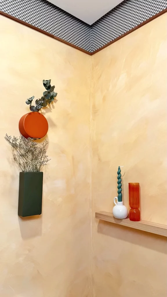 Arranjo de plantas secas na parede pintada de amarelo.