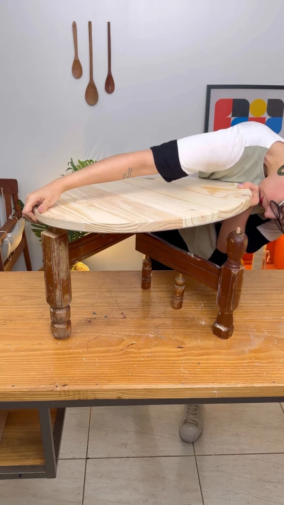 Encaixe do tampo de madeira redondo de madeira clara nos pés da mesa.