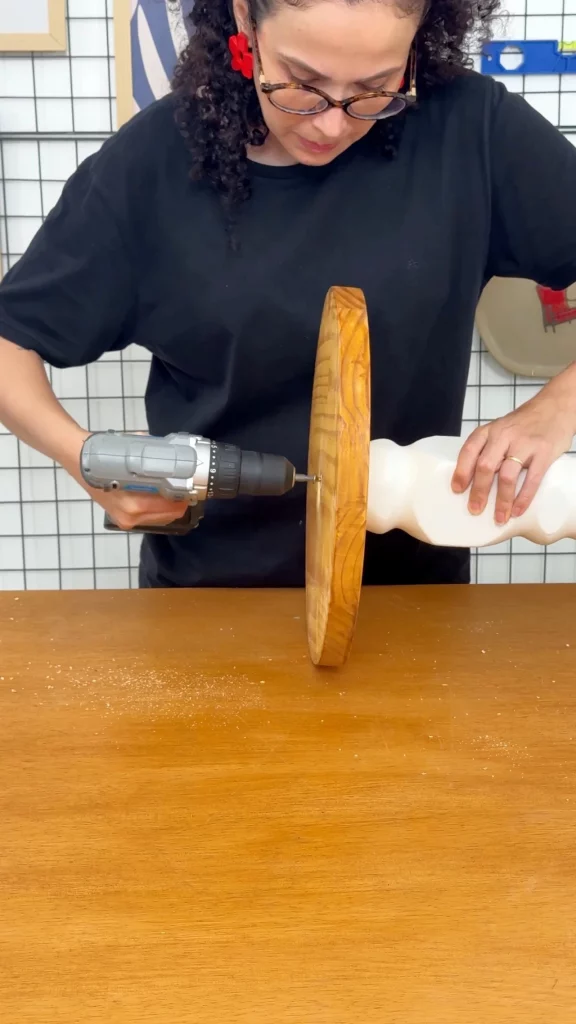 Parafusando a base da luminária, que é um tampo de madeira.