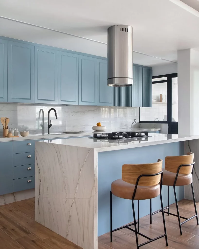 Cozinha com ilha de mármore branco e armários azuis.