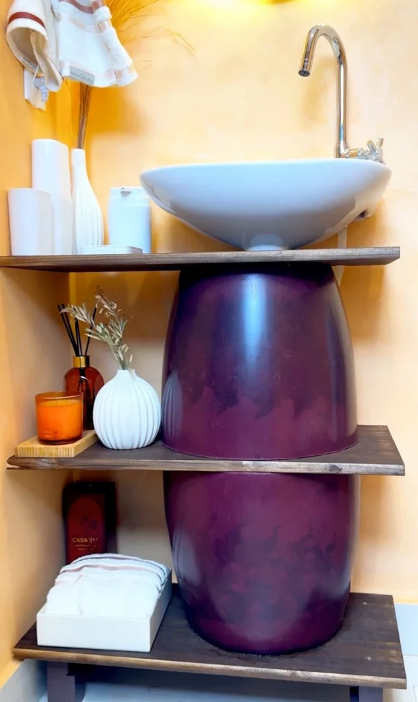 Móvel para embaixo da pia com vaso roxo e tábuas de madeira.