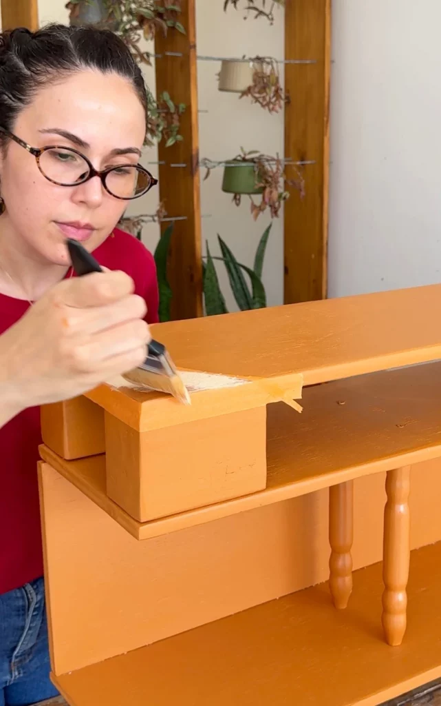 Pintura do aparador nos cantos com pincel e tinta branca.