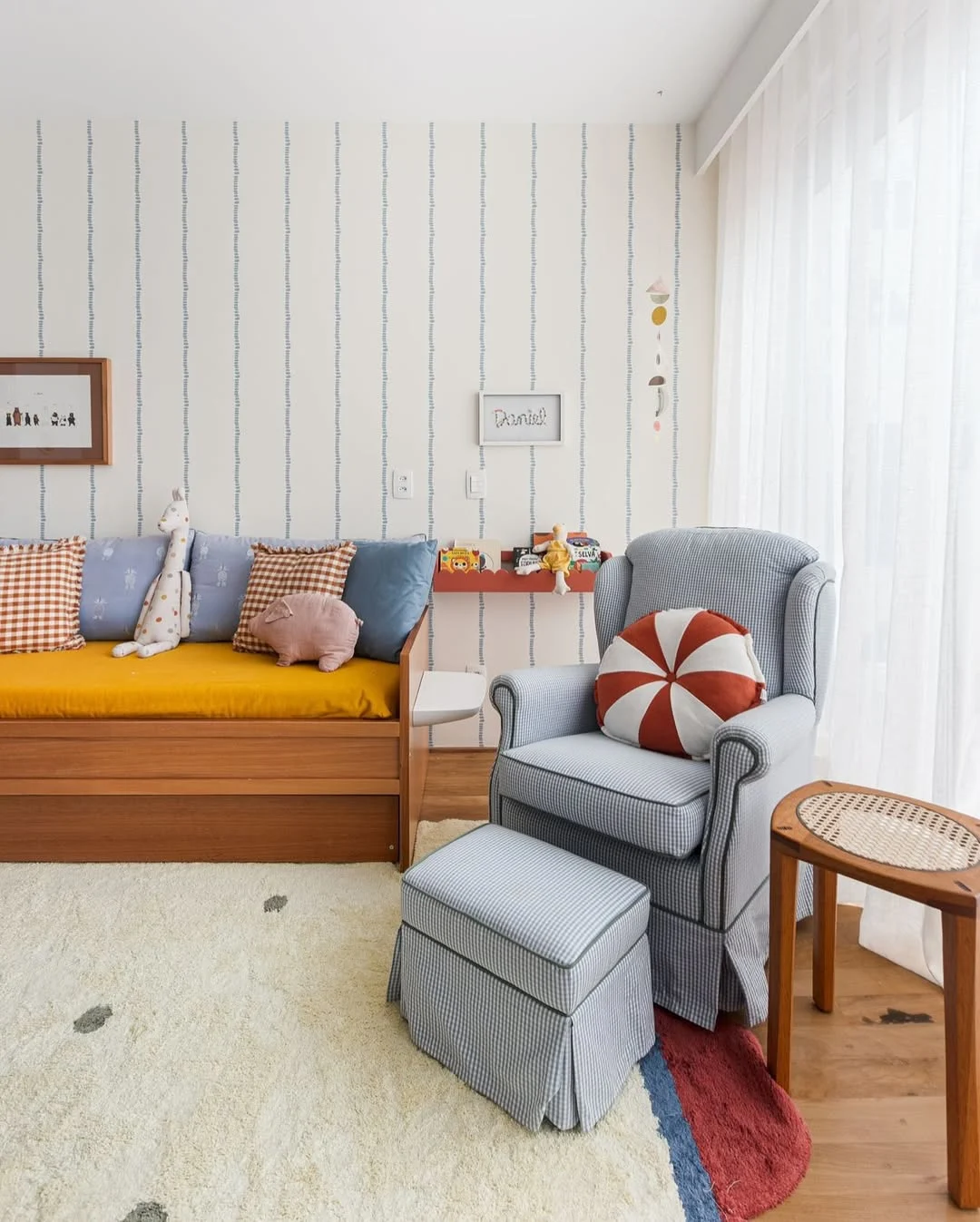 Quarto infantil de bebê com almofada redonda e listrada de vermelho com branco.