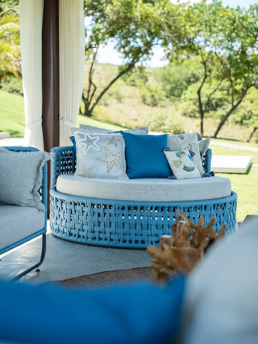 Varanda com sofá redondo e almofadas temáticas de maresia.