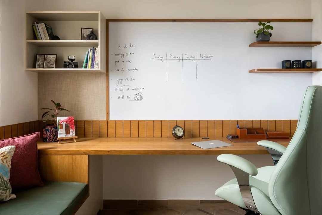 Home office compartilhado, mesa de madeira, cantinho com almofada e cadeira verde.