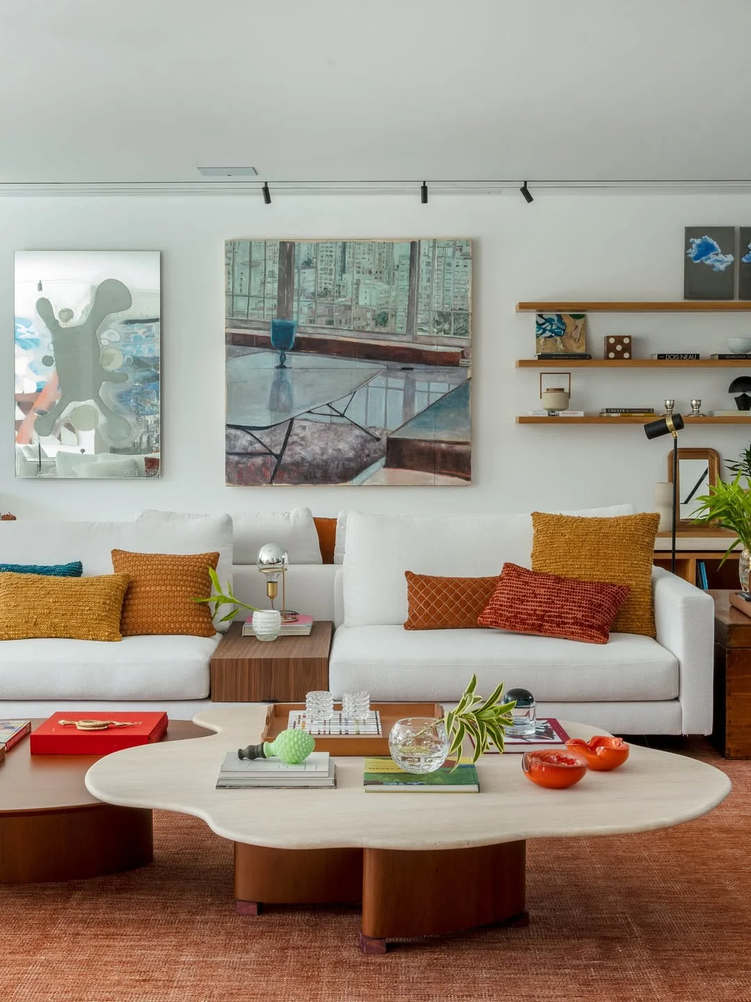 Almofadas coloridas em tons terrosos no sofá branco.