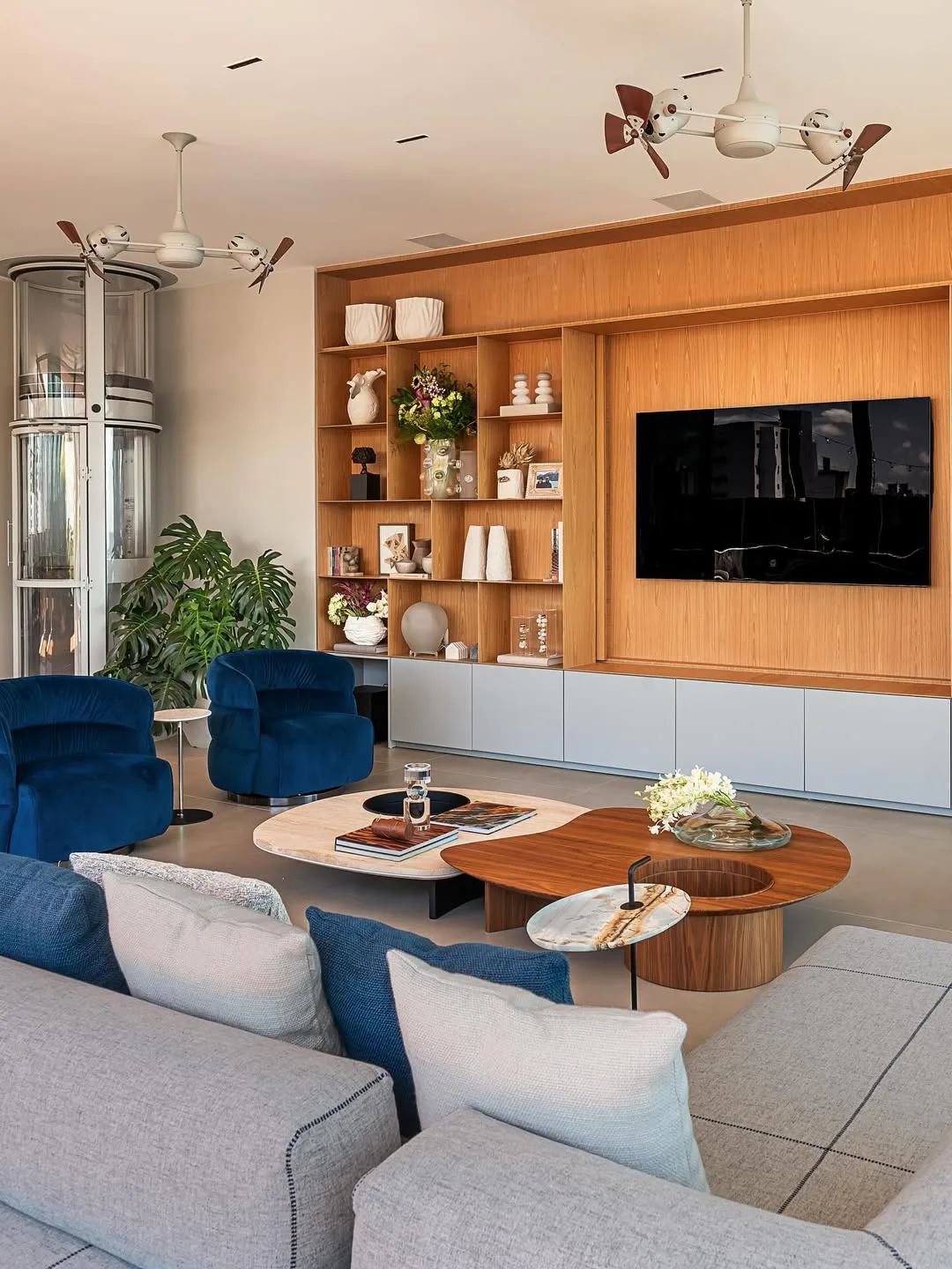 Sofá com almofadas com cores similares da poltrona, painel de madeira com televisão.