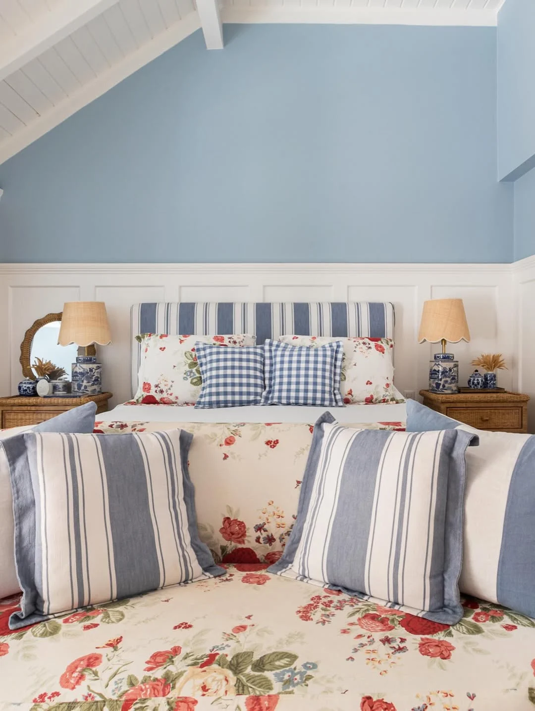 Almofadas, cabeceira e poltrona com estampas variadas, parede azul.