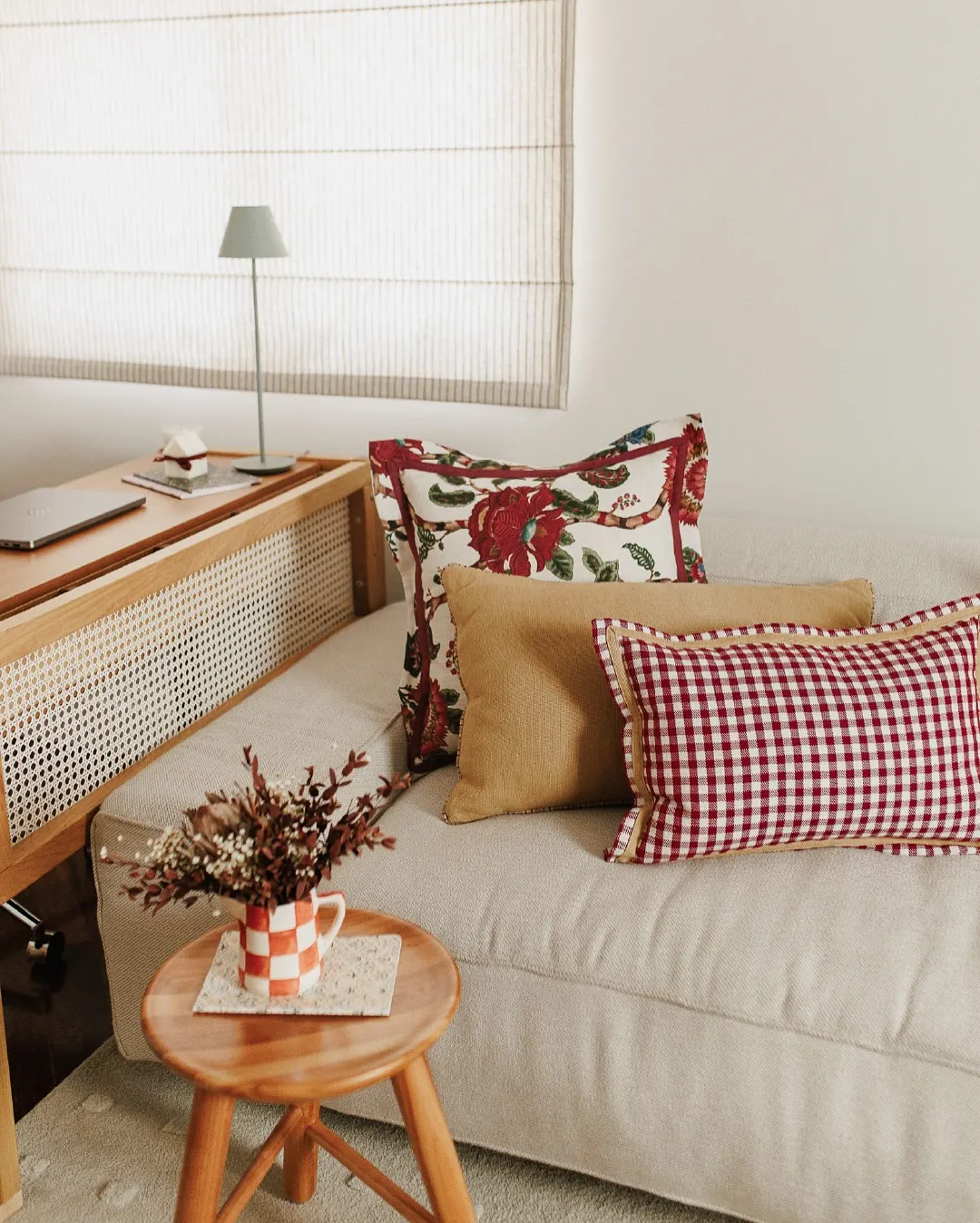 Sofá cor clara neutra e com almofadas estamapdas, vermelho predominante.