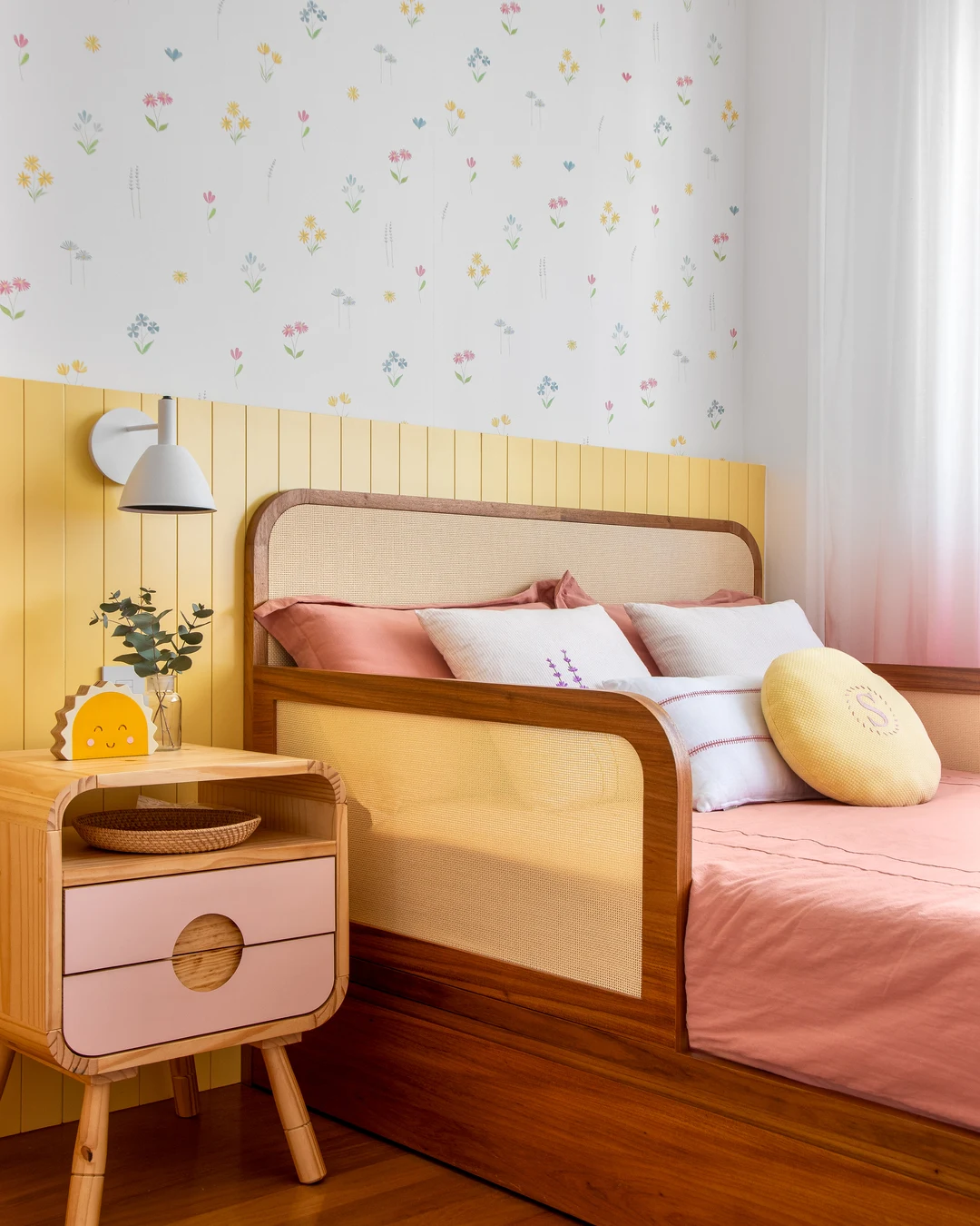 Cama infantil com almofadas coloridas e formatos diferentes.