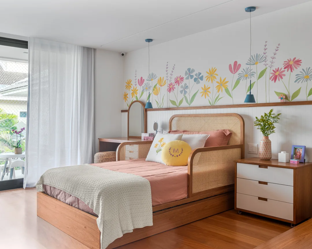 Quarto infantil feminino, papel de parede floral, cama com almofadas coloridas.