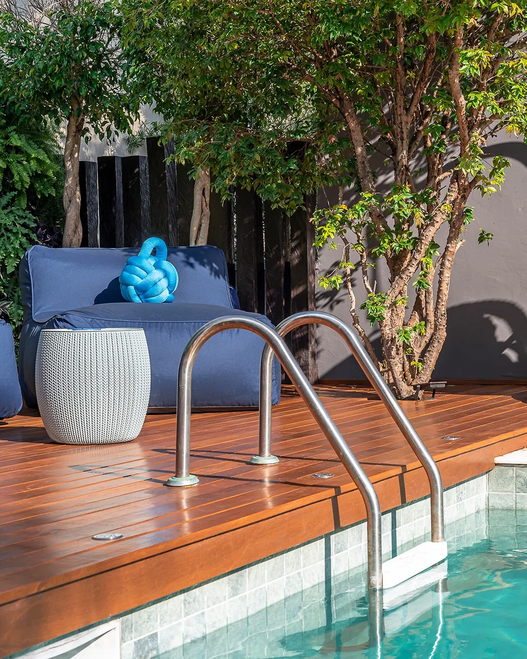 Almofada de nó azul na área piscina, poltrona azul petróleo.