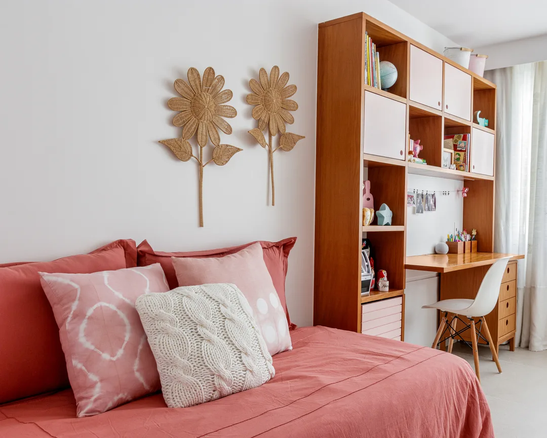 Cama com almofadas texturizadas e em tons de rosa e branco, flores na parede.