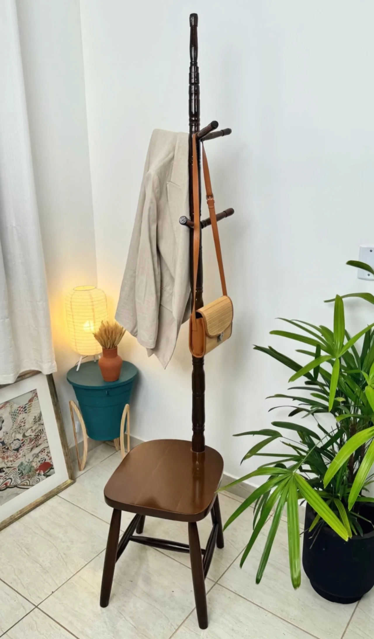 Banco de madeira com cabideiro embutido, bolsa e casaco pendurados.