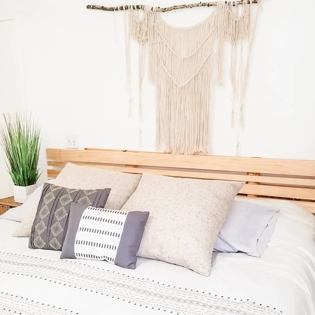 Cama com cabeceira de pallet e estilo boemio.